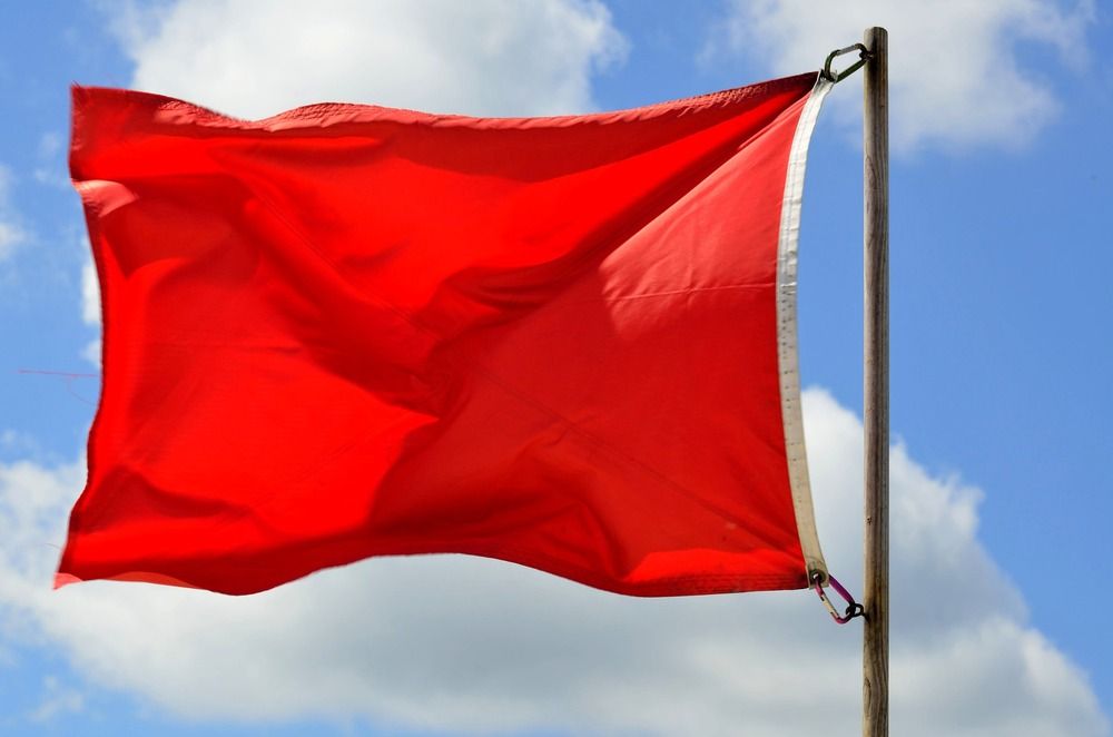 A red flag with a clear blu sky at the back.